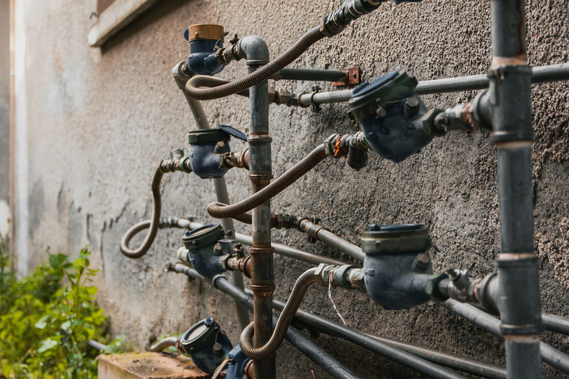 Multiple water meters attached to pipes on a wall